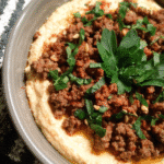 Savory spiced beef over creamy hummus with toasted pine nuts and pita bread