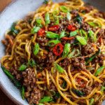 Bowl of sticky beef noodles with scallions