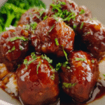 Honey garlic meatballs coated in a glossy sweet–savory sauce in a skillet