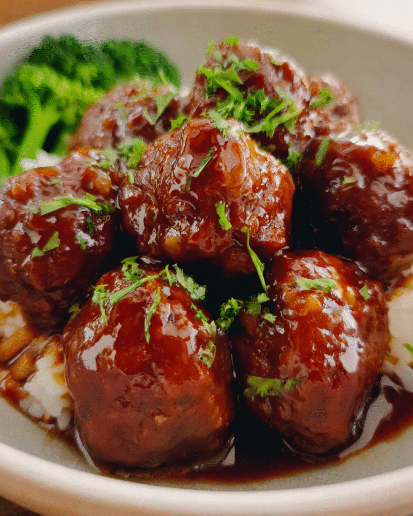 Honey garlic meatballs coated in a glossy sweet–savory sauce in a skillet