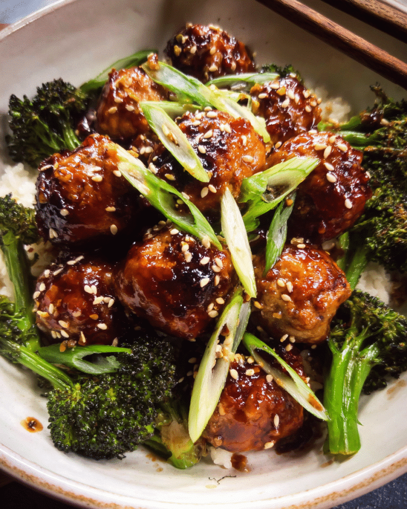 Honey garlic meatballs in a skillet with broccoli and glossy sauce