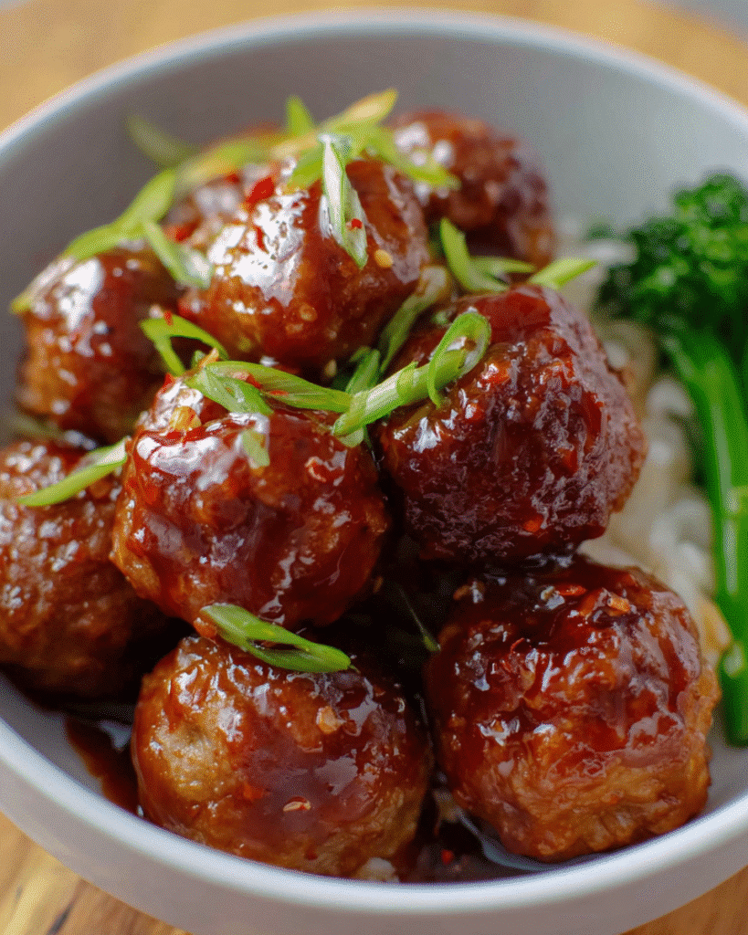 Honey garlic meatballs coated in a glossy sweet–savory sauce in a skillet