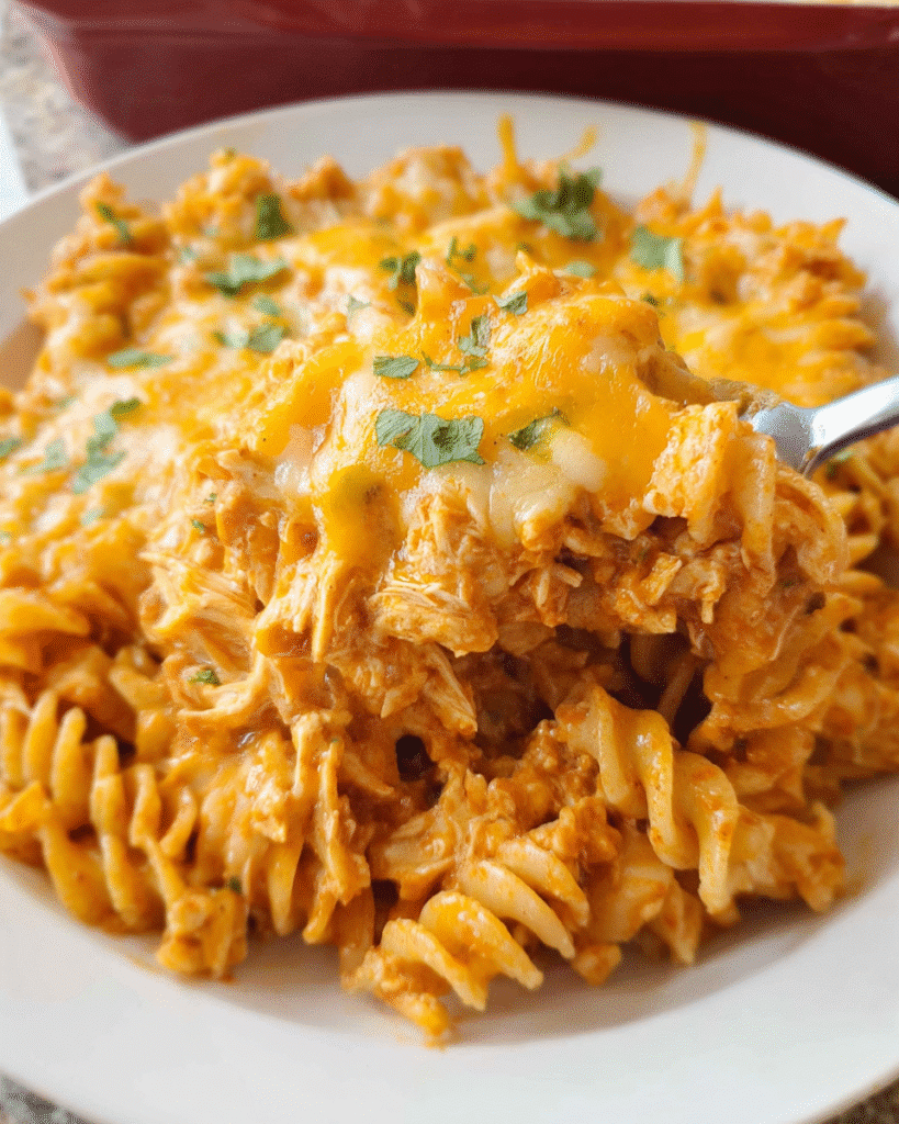 Cheesy Chicken Enchilada Pasta in a casserole dish with melted cheese on top