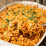 Cheesy Chicken Enchilada Pasta in a casserole dish with melted cheese on top