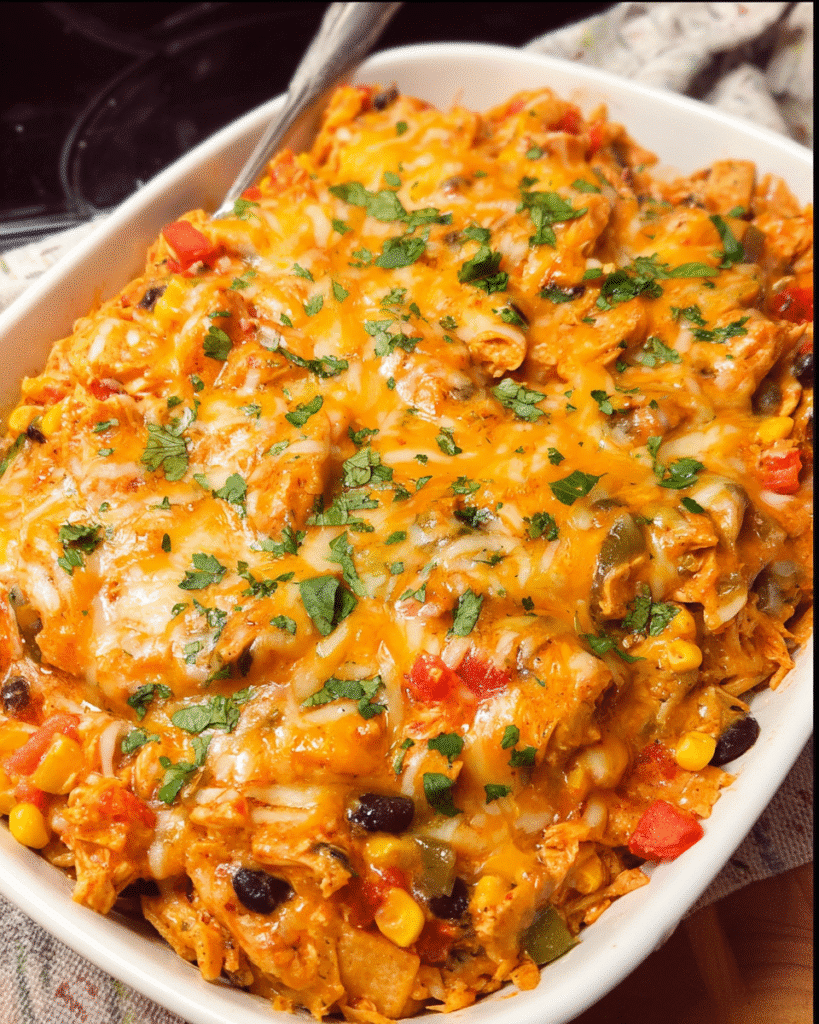 Cheesy chicken taco casserole baked with melted cheese and crushed tortilla chips in a white casserole dish