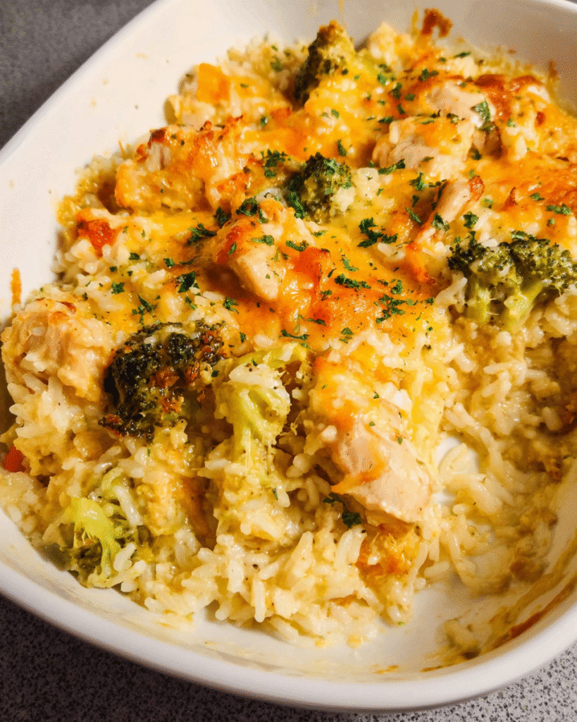 Cheesy chicken and rice casserole in white baking dish, golden melted cheese on top