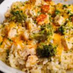 Cheesy chicken and rice casserole in white baking dish, golden melted cheese on top