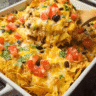 Chicken Nacho Casserole topped with cheese, tomatoes, and jalapeños