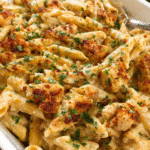 Creamy Cajun Chicken Pasta Bake fresh out of the oven in a white baking dish, bubbling with melted cheese and garnished with parsley.