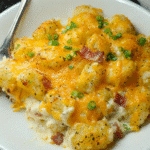 Creamy Chicken Bacon Tater Tot Casserole in a baking dish topped with melted cheese and green onions