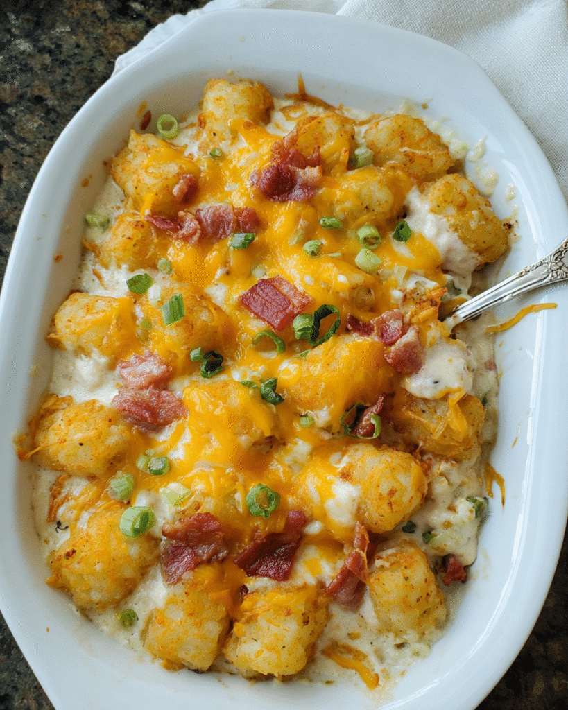 Creamy Chicken Bacon Tater Tot Casserole in a baking dish topped with melted cheese and green onions