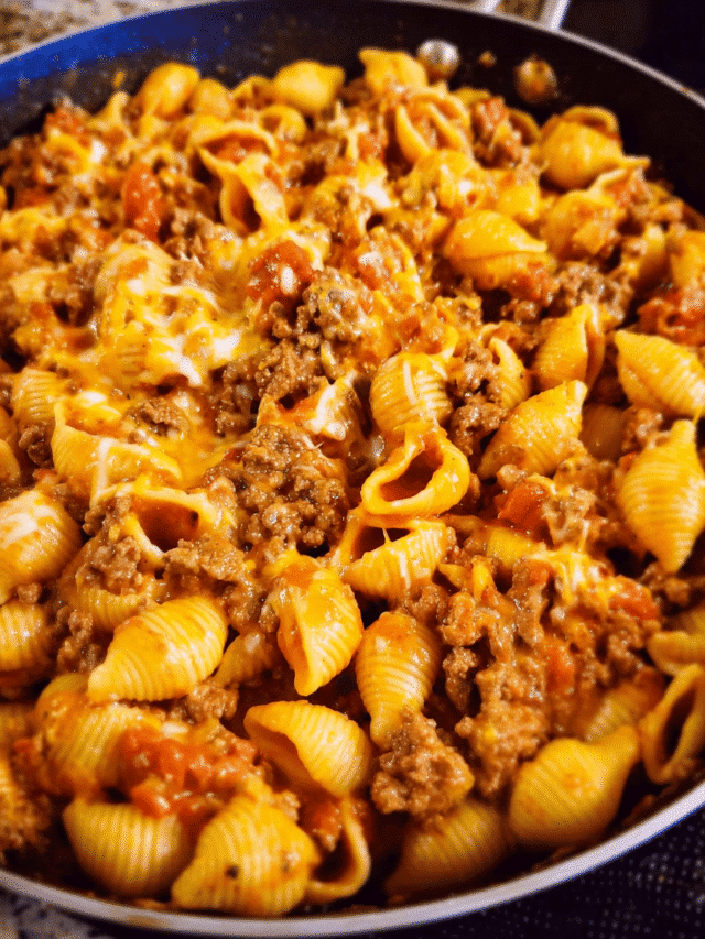 Cheesy taco pasta bake in skillet with melted cheddar and pasta shells