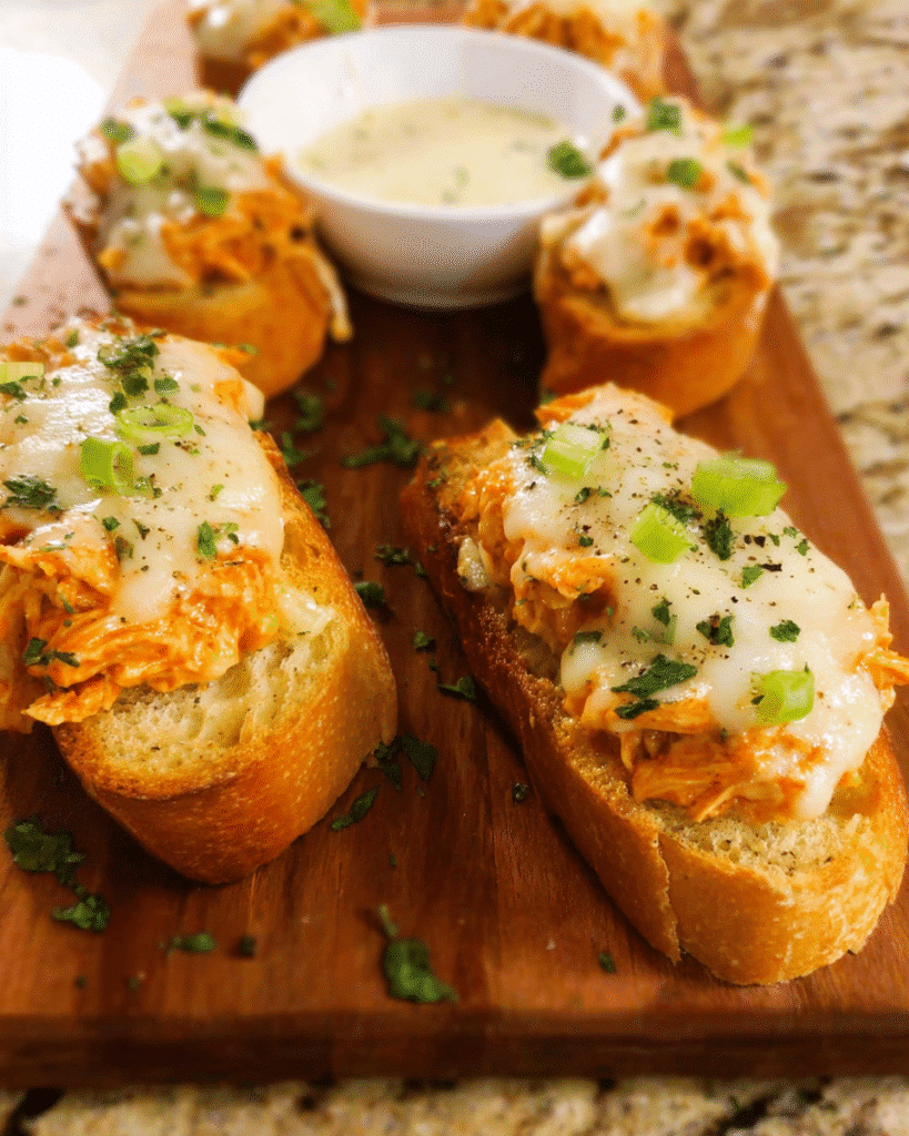 Buffalo Chicken Crostini topped with melted mozzarella and ranch drizzle
