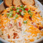 Creamy Garlic Chicken Dip in a bowl garnished with cheddar and green onions
