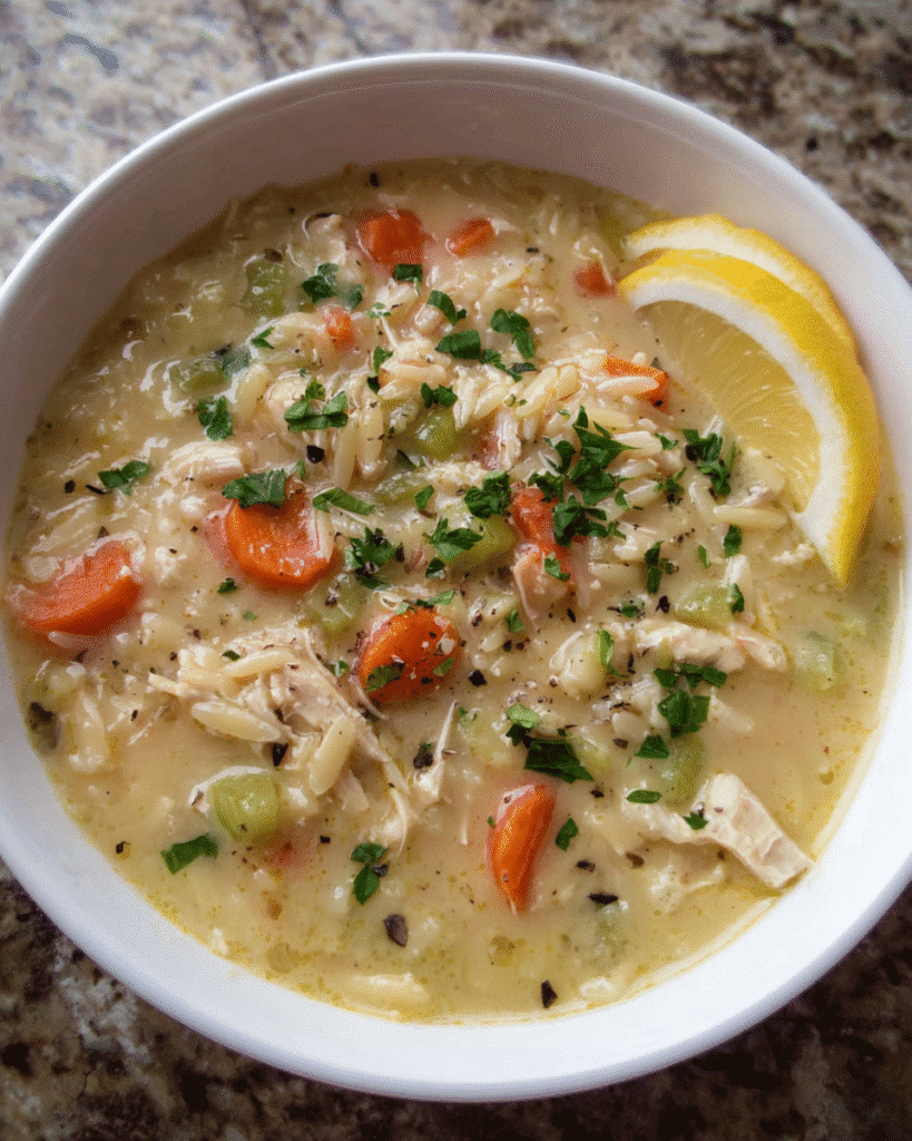 Creamy Parmesan Chicken Orzo Soup served in a white bowl with parsley and parmesan