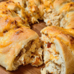 Golden baked cheesy chicken stuffed crescent ring sliced on serving platter