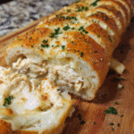 Chicken Alfredo Stuffed French Bread sliced to show creamy chicken and melted cheese filling