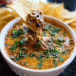 Homemade cheesy chili dip served warm with tortilla chips