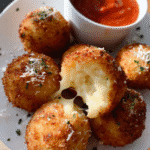 Golden crispy Incredible Arancini stuffed with melted mozzarella and served with tomato sauce