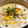 A bowl of creamy corn chowder soup with potatoes and green onions