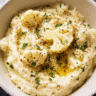 creamy garlic mashed cauliflower in a bowl with herbs