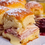 Golden baked Monte Cristo sliders topped with powdered sugar
