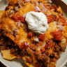 Cheesy baked nacho casserole topped with melted Mexican cheese and tortilla chips