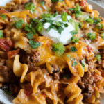 Baked cheesy taco pasta casserole topped with melted cheddar and green onions