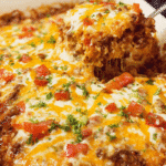 Baked cheesy taco rice casserole topped with melted cheese and fresh cilantro