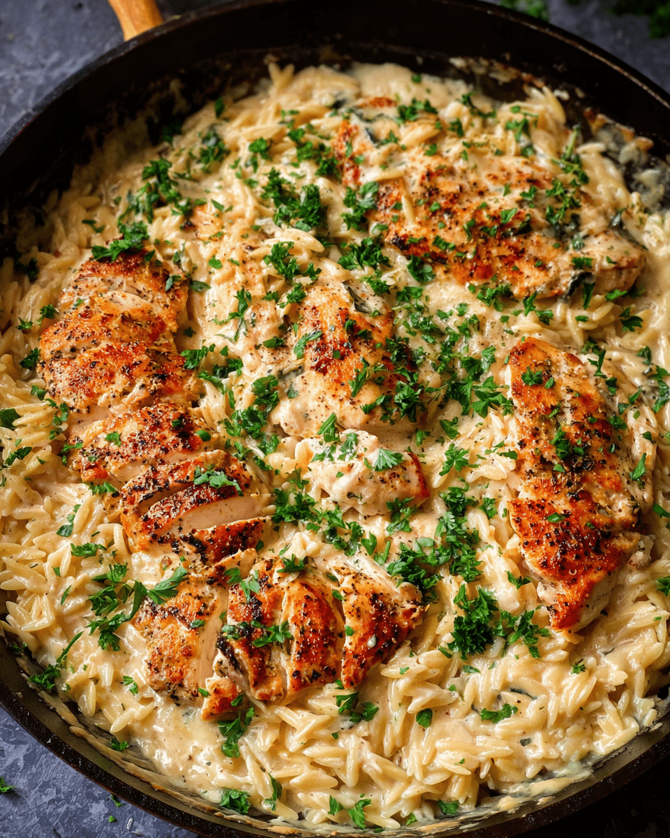 Creamy parmesan chicken orzo served in a skillet with fresh parsley