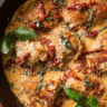 Creamy sun dried tomato chicken in a skillet with Parmesan sauce and basil