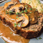 Slice of old fashioned meatloaf with mushroom gravy on a dinner plate