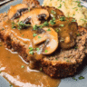 Slice of old fashioned meatloaf with mushroom gravy on a dinner plate