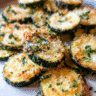 Golden baked parmesan zucchini chips on a serving platter