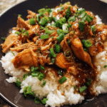 Slow cooker bourbon chicken served over rice with green onions