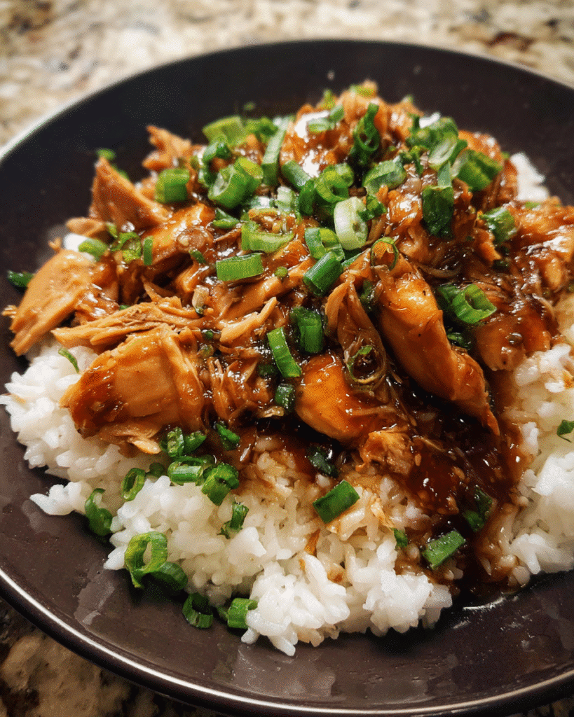 Slow cooker bourbon chicken served over rice with green onions