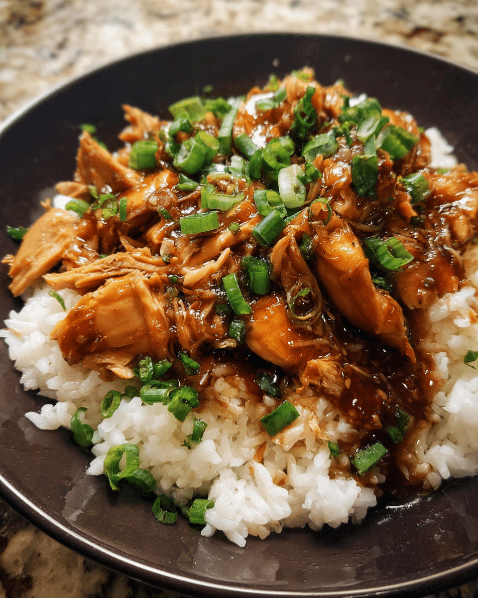 Slow cooker bourbon chicken served over rice with green onions