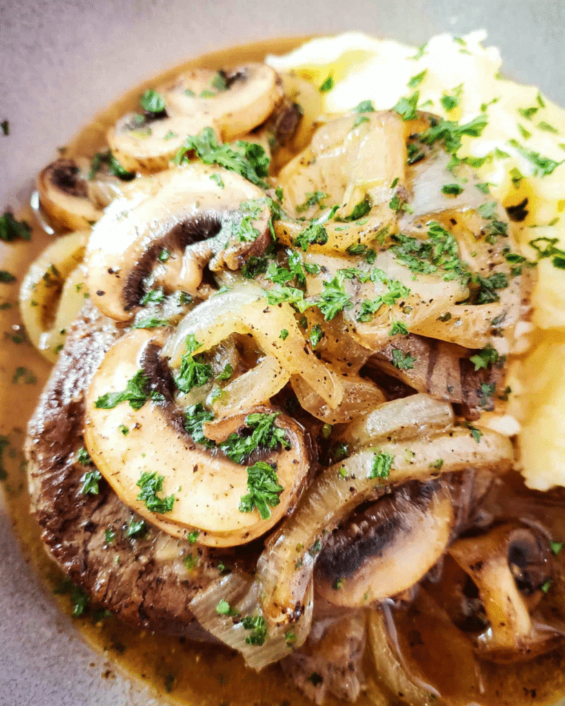 Slow cooker French onion beef served over mashed potatoes with melted Swiss cheese