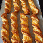 Golden cheesy puff pastry twists freshly baked on a serving tray